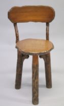 AN OVAL RUSTIC "CUTLERS" CHAIR with curving back, solid seat on three tree trunk legs.