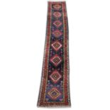 A PERSIAN DESIGN RUNNER, dark blue ground with eight medallions. 14ft 8ins x 3ft.