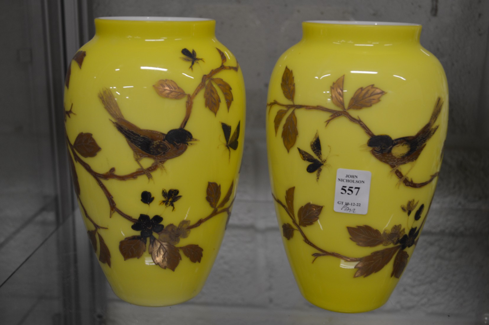 A pair of yellow opaque glass vases, gilt decorated with birds on branches.