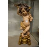 A carved painted and gilded model of a cherub.