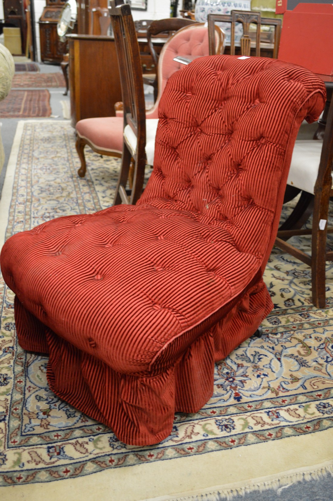A Victorian button upholstered nursing chair upholstered in a red velveteen fabric.