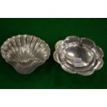 A small silver dish and a silver shell shaped dish.