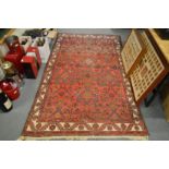 A Persian carpet, red ground with stylised decoration 220cm x 130cm.