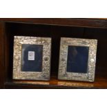 A pair of small silver photograph frames with embossed decoration.