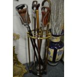 A brass and cast iron circular stick stand with various sticks and shooting sticks etc.