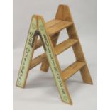 A PAIR OF NOVELTY CHAMPAGNE WOODEN FOLDING STEPS. 30ins high.