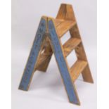 A PAIR OF NOVELTY CHAMPAGNE WOODEN FOLDING STEPS. 30ins high.