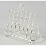 A SILVER PLATED CROSS GUNS SIX DIVISION TOAST RACK on ball feet. 7.5ins long.