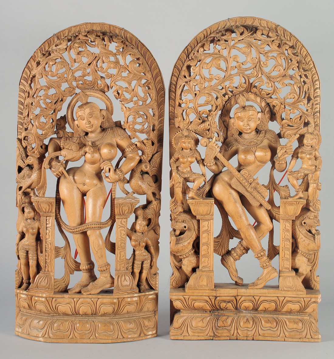 A PAIR OF THAI WOODEN WALL CARVINGS, each depicting a deity amongst pierced foliate decoration, each