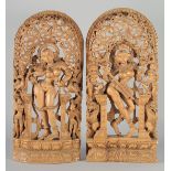 A PAIR OF THAI WOODEN WALL CARVINGS, each depicting a deity amongst pierced foliate decoration, each