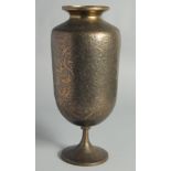 A TALL ISLAMIC ENGRAVED BRASS PEDESTAL VASE, the engraved and chased decoration depicting deities