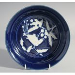 A RARE CHINESE BLUE AND WHITE RESERVE-DECORATED PORCELAIN DISH, the centre with a bird and flora,