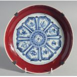 A CHINESE BLUE, WHITE AND COPPER RED DISH, decorated with radiating medallion to the centre,