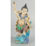 A CHINESE FAHUA FIGURE, standing on a fish, 27cm high.