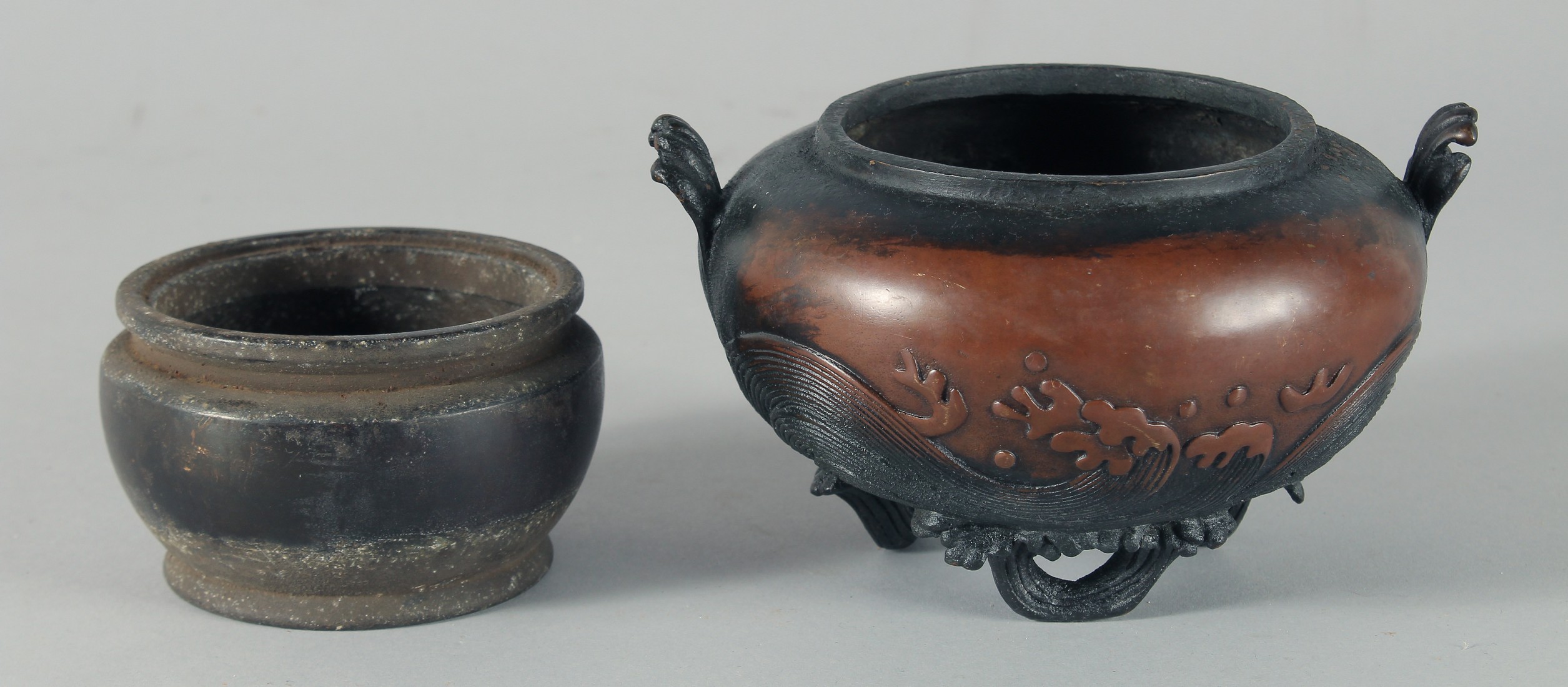 A CHINESE BRONZE TWIN HANDLE CENSER, with relief decoration of stylised waves and raised on three