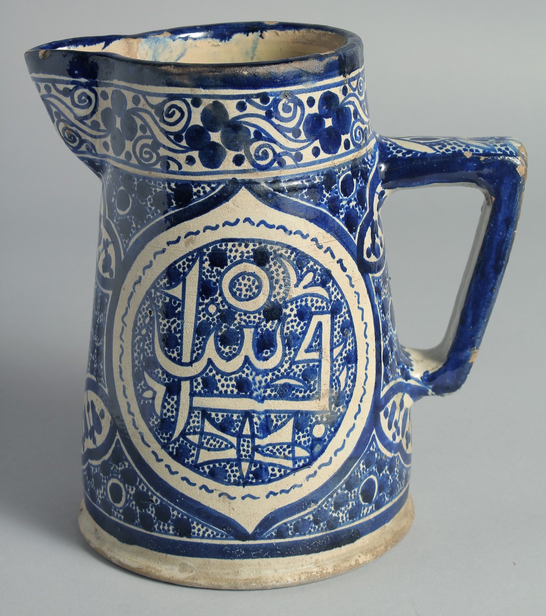 AN ISLAMIC BLUE AND WHITE GLAZED POTTERY EWER, 20.5cm high.