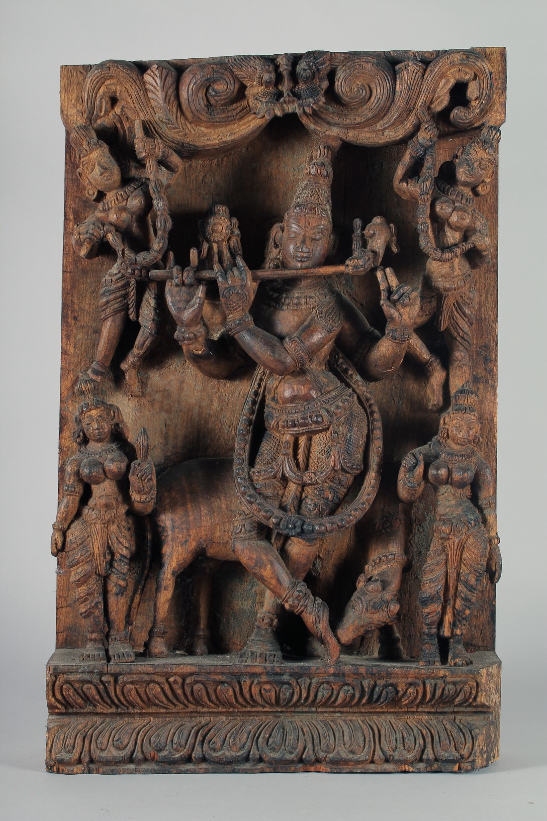 A LARGE INDIAN CARVED WOODEN PANEL, with central deity playing a musical instrument surrounded by