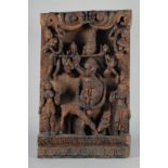 A LARGE INDIAN CARVED WOODEN PANEL, with central deity playing a musical instrument surrounded by