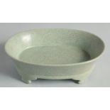 A CHINESE CELADON CRACKLE GLAZE OVAL FORM BRUSH WASHER, raised on four feet, 20cm wide.