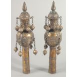 A PAIR OF ISLAMIC BRASS CEREMONIAL FINIALS, each with hanging bells and inset with turquoise stones,