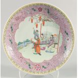 A LARGE CHINESE FAMILLE ROSE PORCELAIN DISH, painted with a central panel of figures in a garden