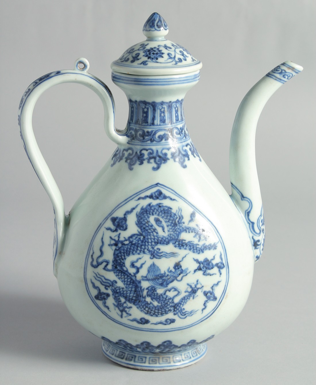 A CHINESE MING STYLE BLUE AND WHITE PORCELAIN LIDDED EWER, decorated with dragons, 27cm high.