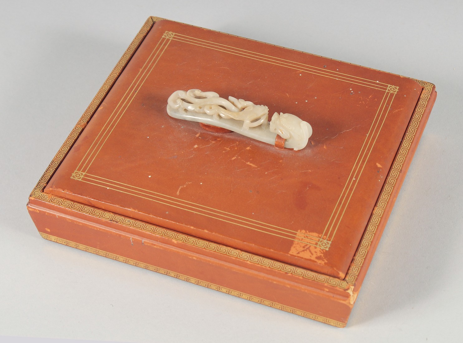 A CHINESE SQUARE FORM LIDDED BOX WITH MOUNTED CARVED JADE BELT HOOK HANDLE, the lid opening to