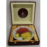 Cased Chinese ceramic plate with raised chrysanthemum decoration (30cm wide) in wooden