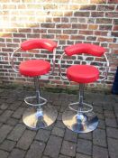 Pair of red gas lift bar stools - one has loose base