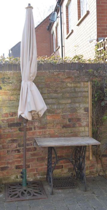 Table made from a treadle sewing machine base & a garden parasol with cast iron base