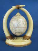 Resin horns with hanging ostrich egg decorated with a transfer print map approx. 26cm tall