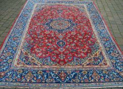 Red & blue ground Persian carpet with floral medallion design 308cm by 221cm