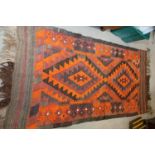 A kelim rug with two diamond lozenges in shades of red, orange, brown and purple, 38" x 78" approx
