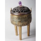 A Chinese brass censor with engraved decorated and carved wooden top and amethyst knop, on three