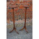 A pair of mahogany torcheres with faux bamboo turned columns, on tripod splay supports with brass