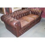A leather chesterfield three-seat settee, button upholstered in a burgundy leather, 76" long x 38"