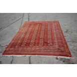 A Bokhara rug decorated seventy-six guls on a rust ground, 73" x 108" approx
