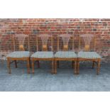 A set of four H J Berry polished as oak pierced splat back dining chairs with tapestry seats, on