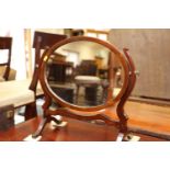 A mahogany oval swing frame toilet mirror, on splay supports, 20" wide x 18 1/2" high overall, and a
