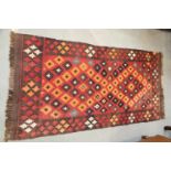 A kelim rug with all-over stepped medaillions on a red ground, 33" x 67"