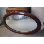 A grained as mahogany oval framed wall mirror, bevelled plate 25 1/2" x 15"