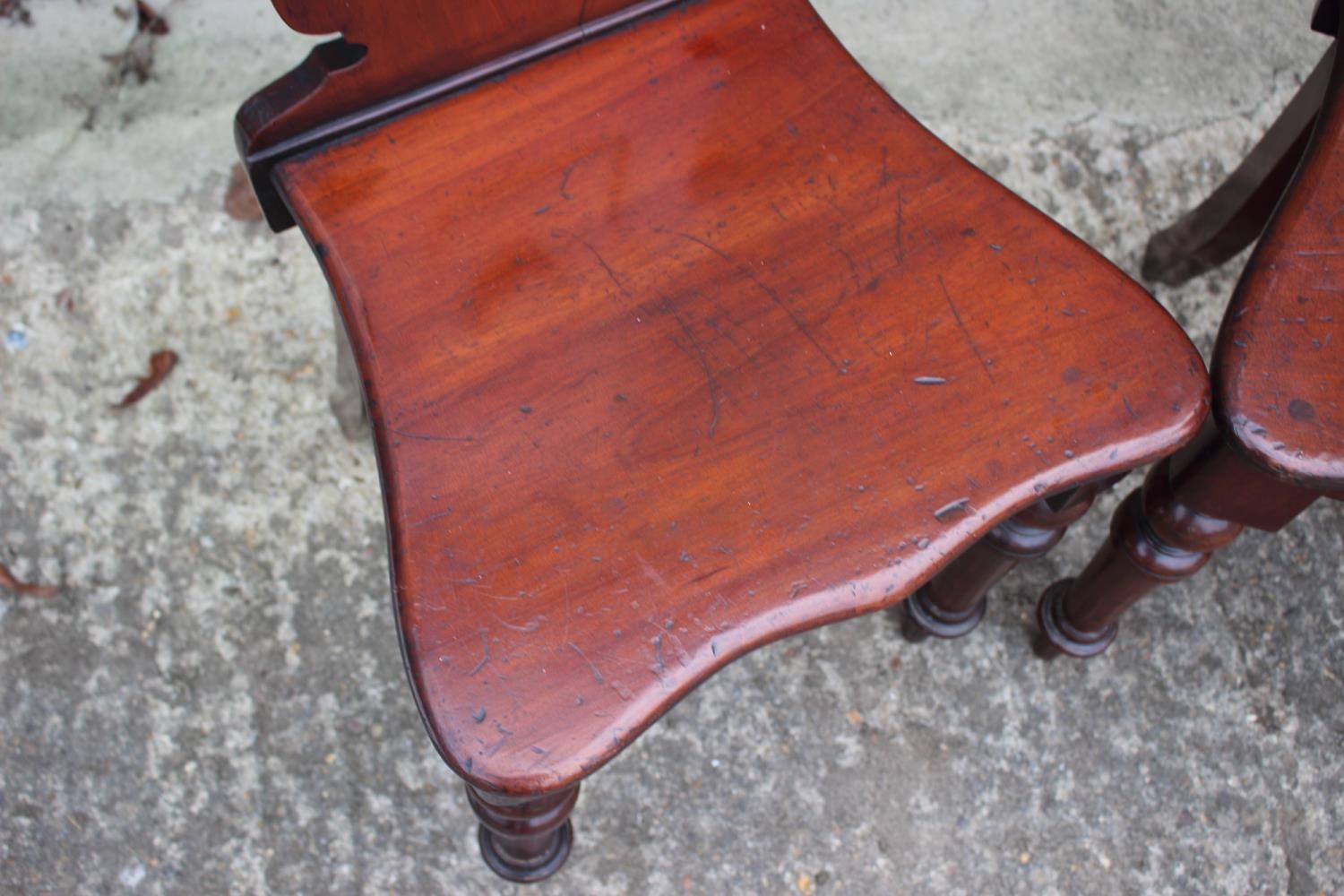 A pair of 19th century carved mahogany hall chairs with shaped panel backs, on turned supports - Image 4 of 6