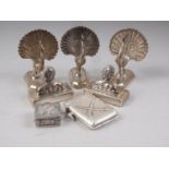 Three white metal menu holders, formed as peacocks, a pair of menu holders with the bust of a