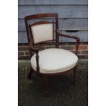 An Edwardian walnut and inlaid showframe shaped low seat armchair with padded seat and back, on