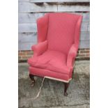 A wing armchair of Georgian design with loose seat cushion, on cabriole supports