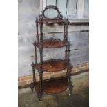 A late 19th century figured walnut four-tier shape front whatnot with oval mirror over spiral turned