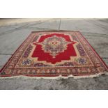 A wool pile rug of Persian design with central medallion on a crimson ground