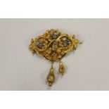 A mid 19th century yellow metal scroll and leaf brooch set diamonds with two pendant drops, in