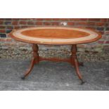 A mahogany and leather inset oval coffee table, on twin turned and stretchered supports, 34" long