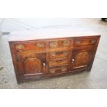 A Georgian oak dresser base, fitted three drawers over three small drawers with flanking cupboards